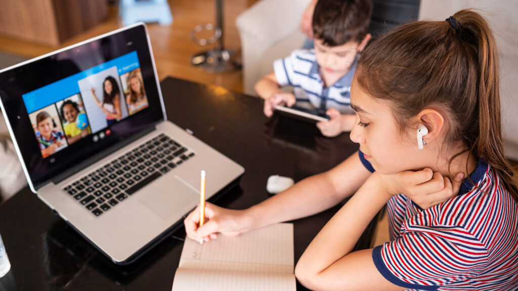 Young girl taking notes from a video on a laptop.